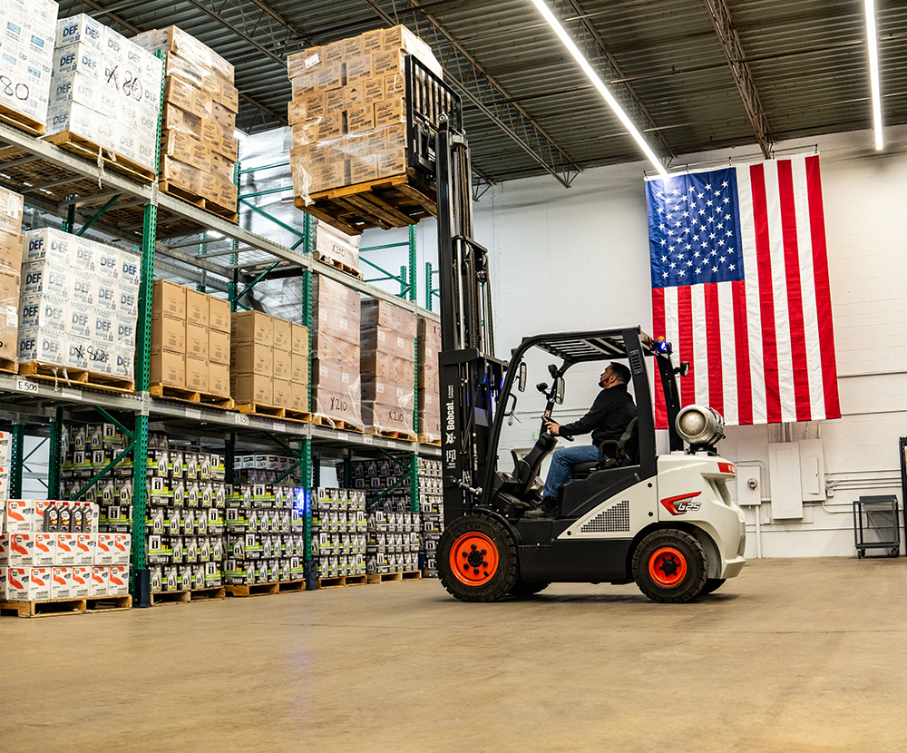 Auto supply warehouse manager operates forklift to move packaged oil