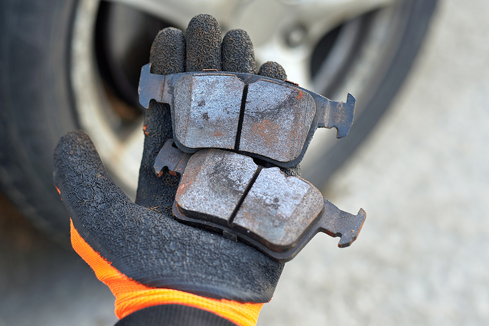 Auto repair technician inspects worn brake pads