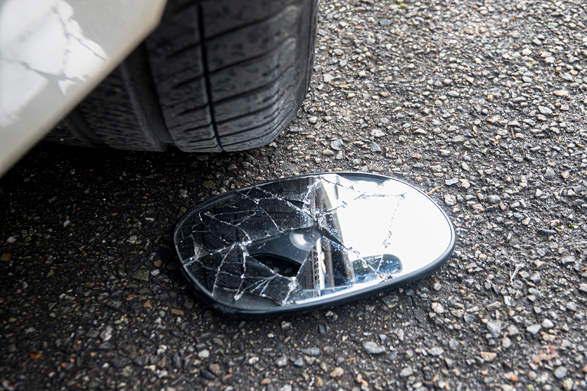 Broken sideview mirror lays on the ground after a sideswipe incident