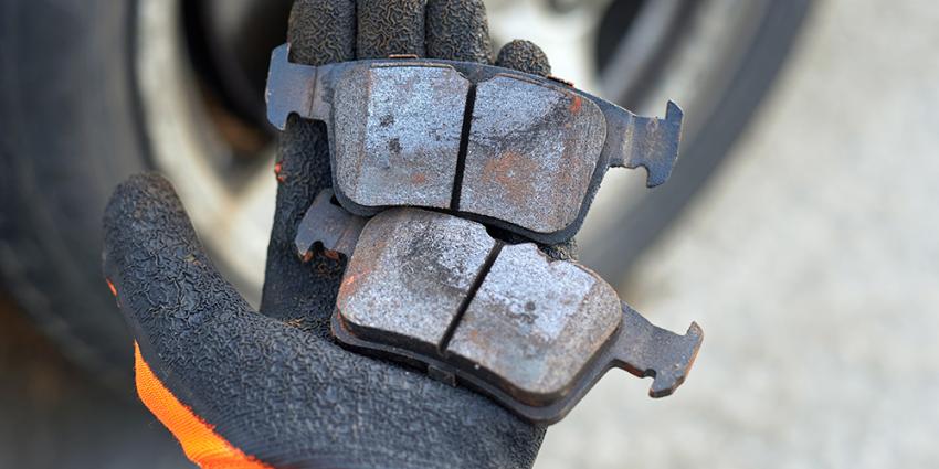 Auto repair technician inspects worn brake pads