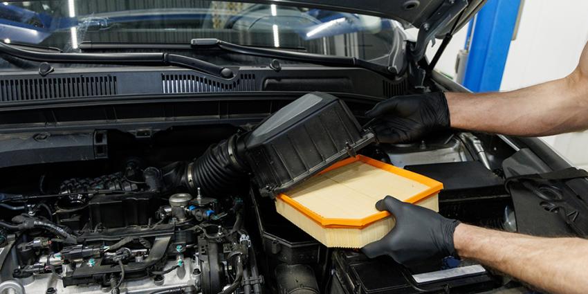 Auto repair technician changes the air filter in a vehicle