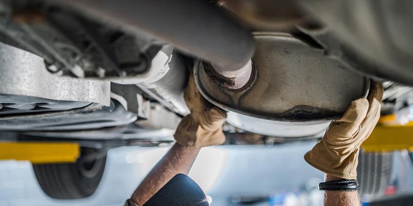 An automotive technician inspects a vehicle's exhaust system