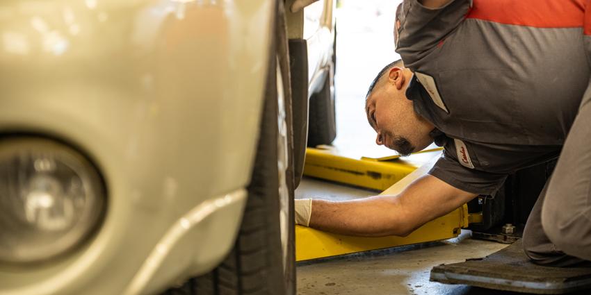 Auto repair technician inspects under a vehicle