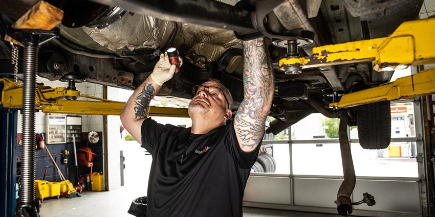 Metro Motor technician inspects underside of vehicle at auto repair shop in Washington DC