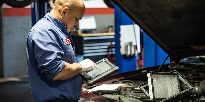 An auto repair technician uses an iPad to scan and diagnose needed vehicle repairs