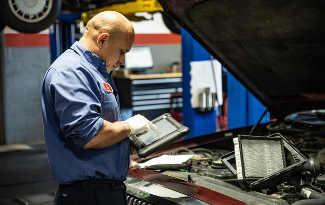 An auto repair technician uses an iPad to scan and diagnose needed vehicle repairs